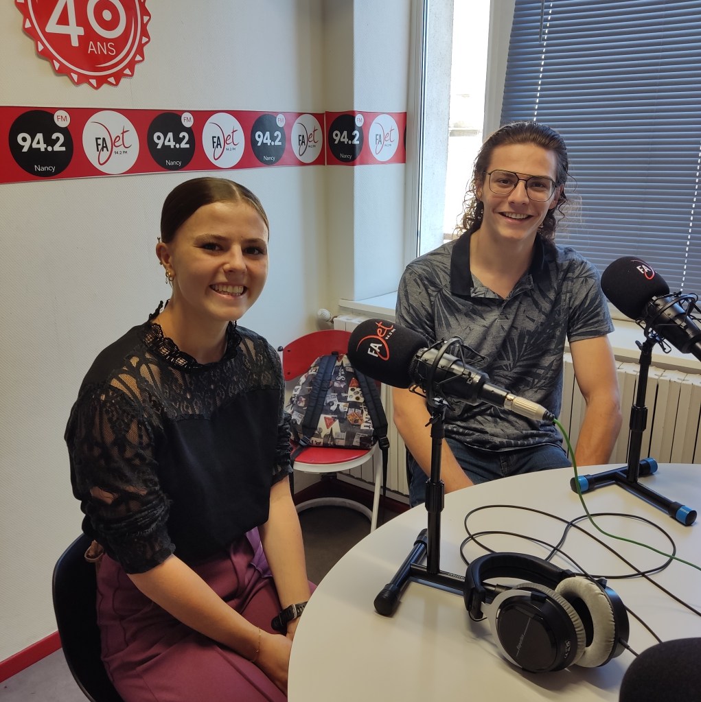 Andrea et Tom, frère et sœur, souriant pendant une émission de radio dans un studio, avec des microphones et des casques sur la table.