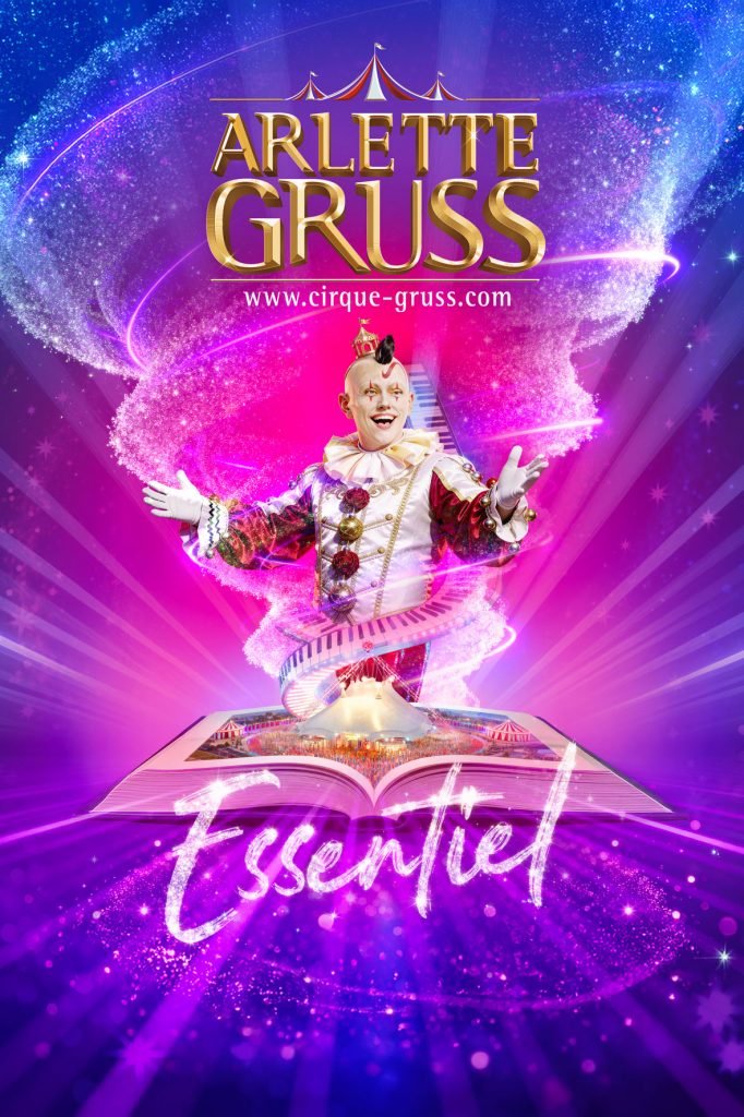 Un clown joyeux en costume coloré, entouré d'effets visuels scintillants, présente le spectacle 'Essentiel' d'Arlette Gruss sur un fond étoilé.