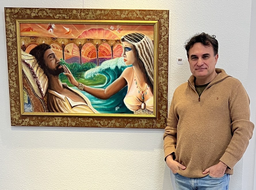 Une peinture colorée représentant une femme et un homme dans une scène romantique, avec des vagues en arrière-plan. L'homme semble être assis, tandis que la femme le touche doucement au visage. Un homme se tient à côté de la peinture.