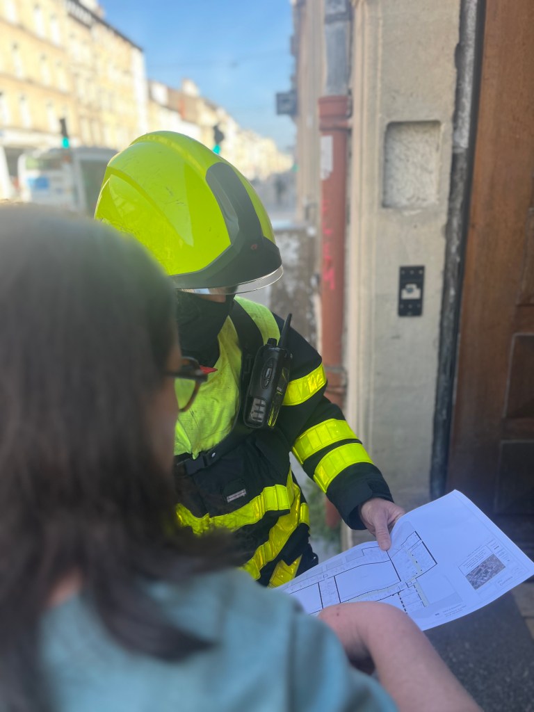 Un pompier en uniforme fluorescent discute avec une personne tout en consultant une carte.